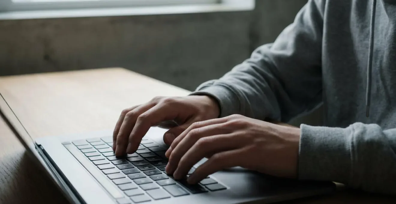A thoughtful teenager's hands typing on a laptop keyboard with soft natural lighting creating shadows, representing the permanent digital traces created online